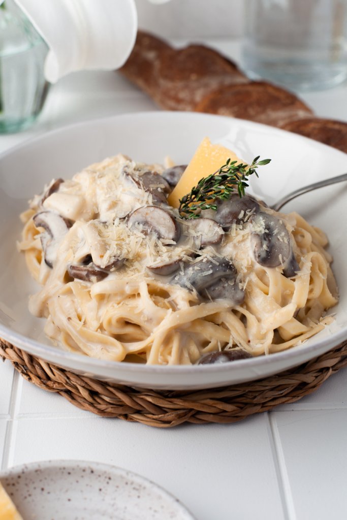 creamy mushroom pasta in a white bowl with a fork