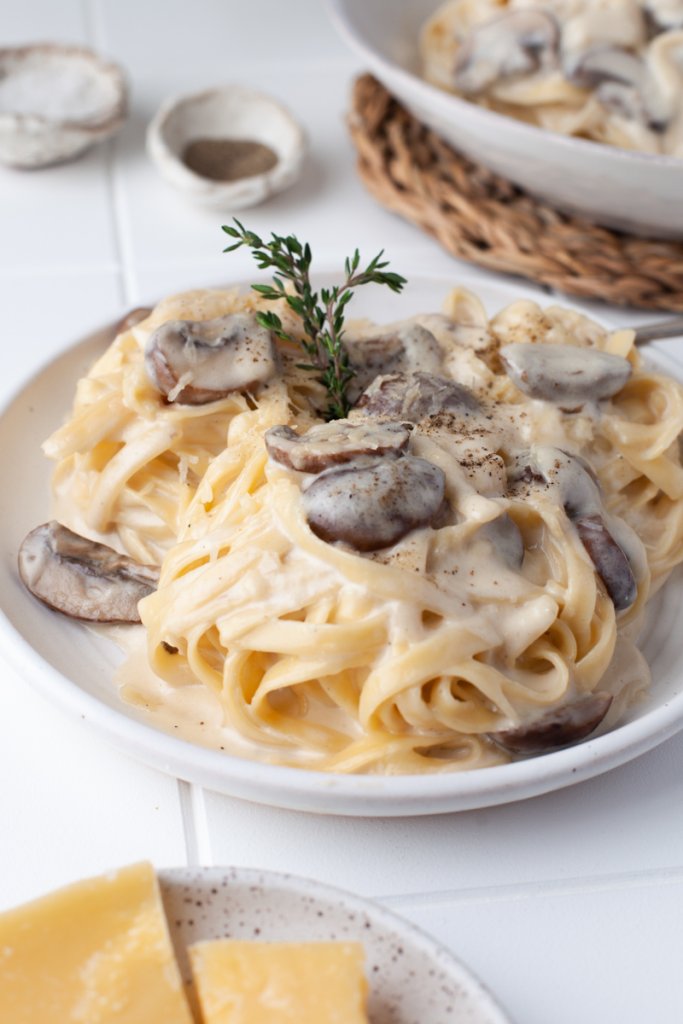 two bowls of creamy mushroom pasta with fresh thyme