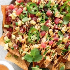 tuna poke nachos on a plate with spicy mayo on the side