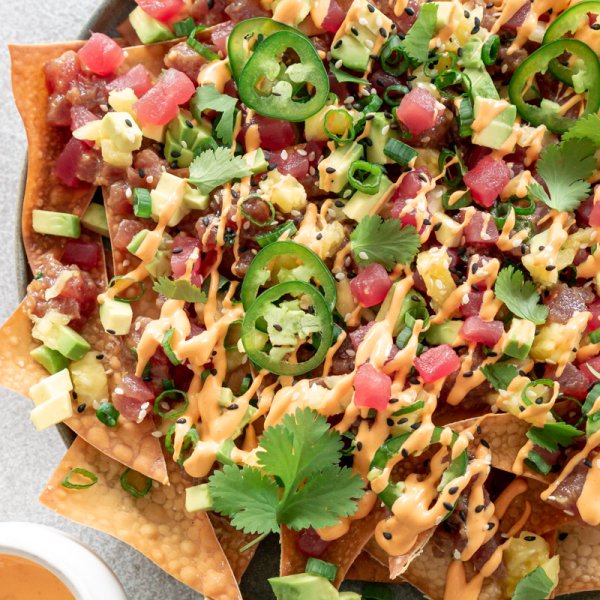 tuna poke nachos on a plate with spicy mayo on the side