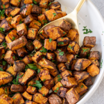 air fryer sweet potato cubes in a white bowl with a serving spoon