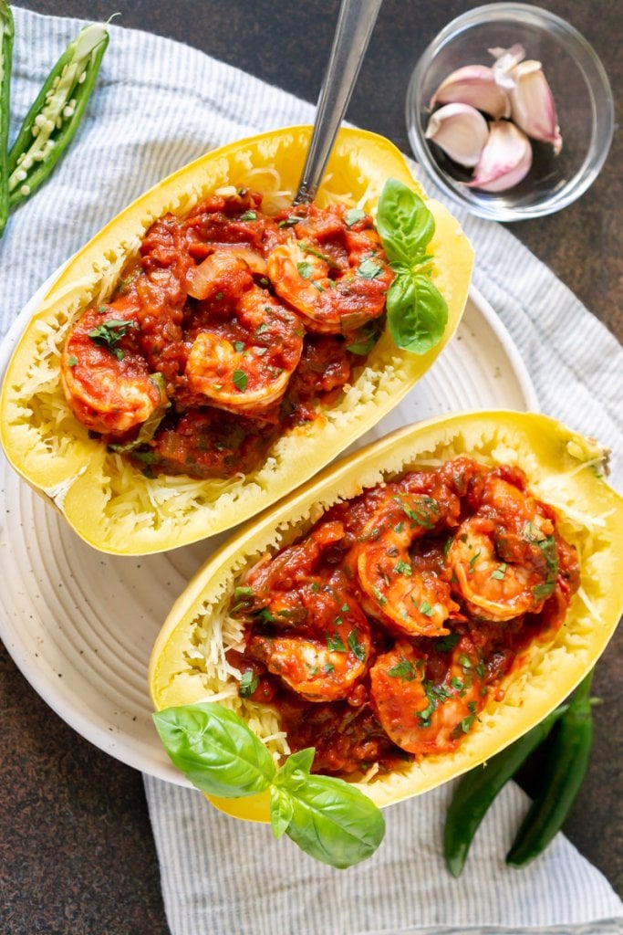 two baked spaghetti squash marinara boats on a white plate with a fork