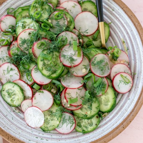 cucumber radish salad in a bowl with a gold and black spoon