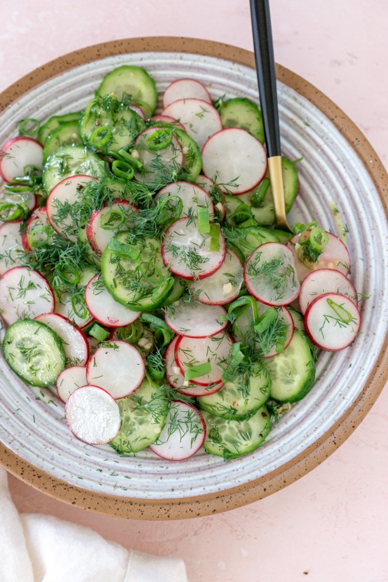 cucumber radish salad in a bowl with a gold and black spoon