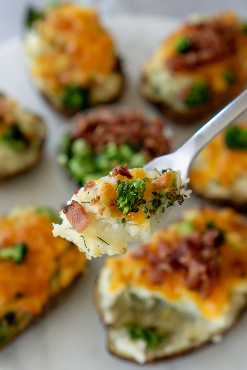 Mashed potatoes with broccoli and bacon on a fork.