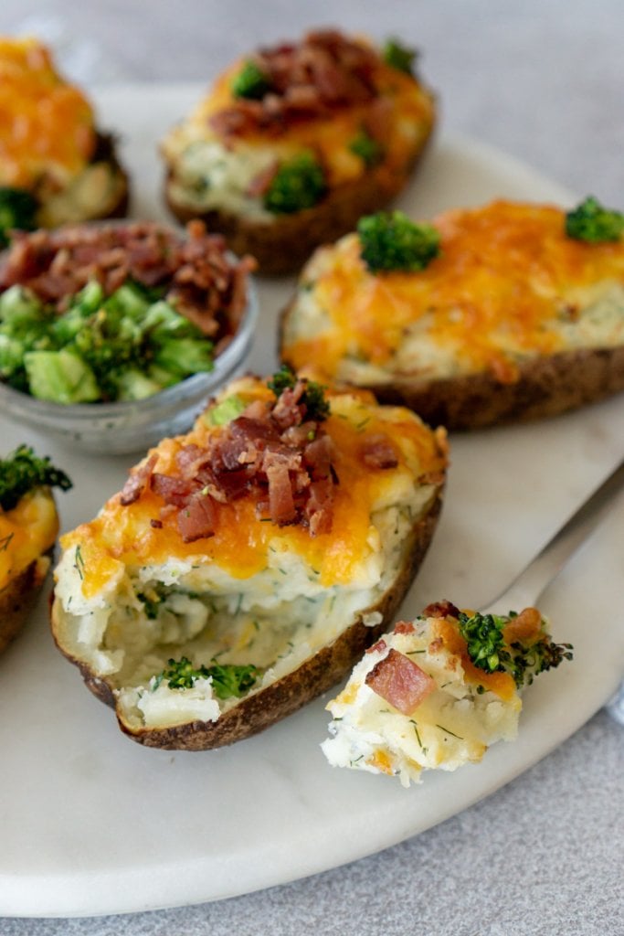 twice baked potatoes on a marble platter and a fork with a bite on it