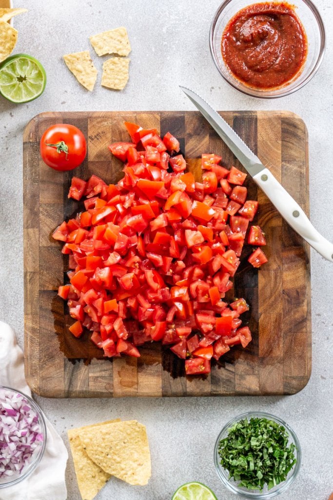 diced tomatoes on a cutting board with a serrated knife