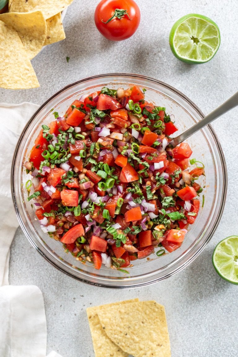 homemade chunky salsa in a glass mixing bowl with a spoon