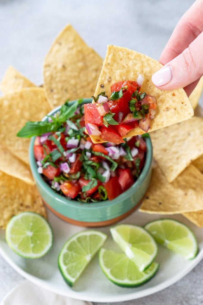 hand dipping a chip in salsa