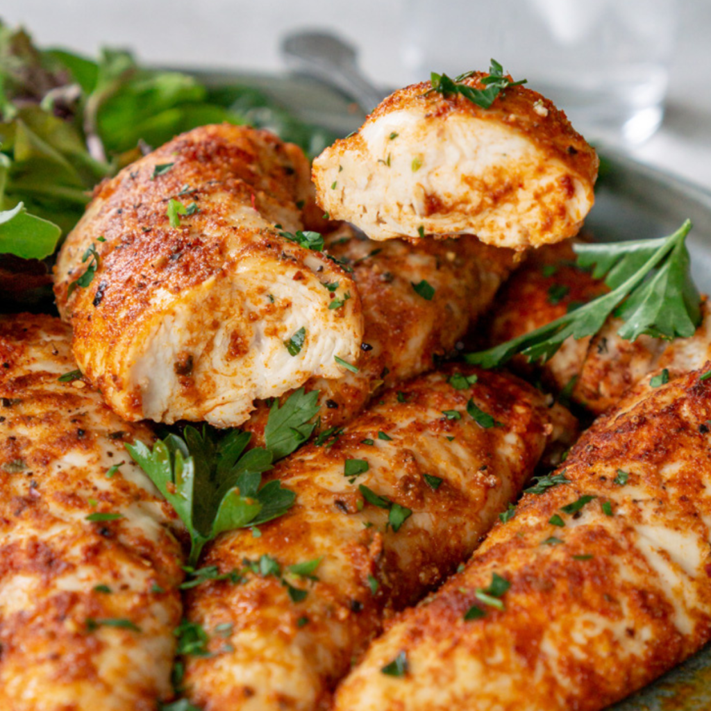 Oven baked chicken tenders on a plate topped with parsley.