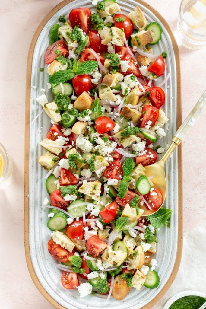 panzanella salad on a large serving plate with two glasses of water on the side