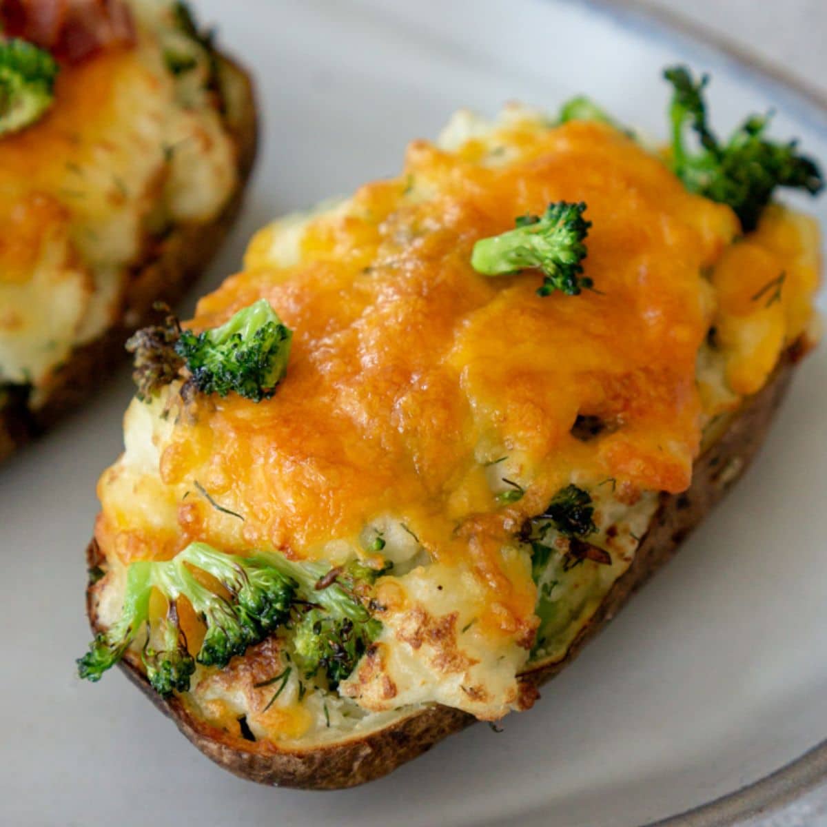 Air fryer twice baked potato with cheese and broccoli on a white plate.