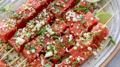 watermelon tajin skewers on a serving plate with lime wedges