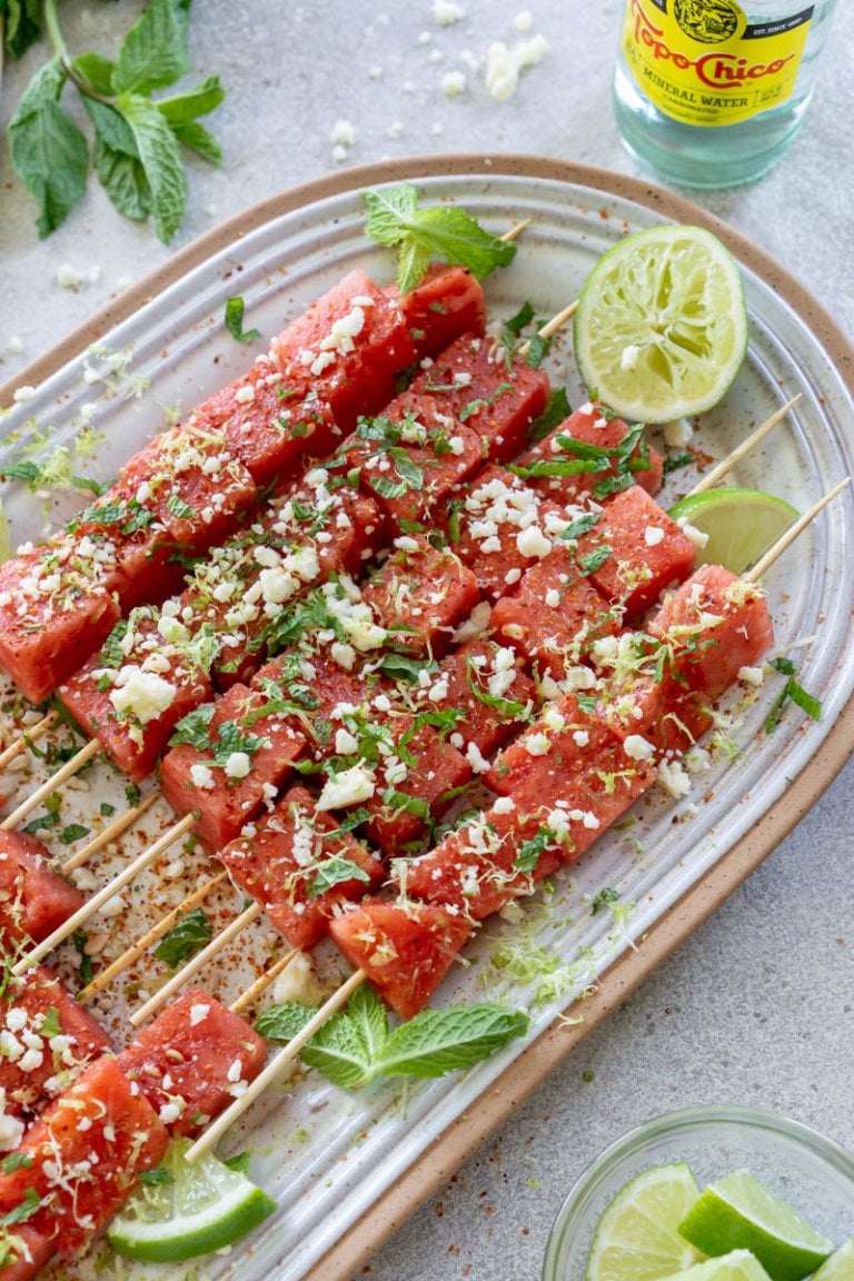 watermelon tajin skewers on a serving plate with lime wedges