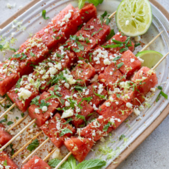 watermelon tajin skewers on a serving plate with lime