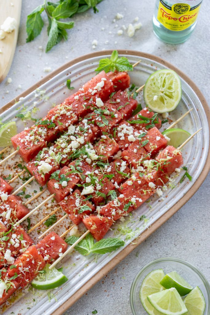 watermelon skewers on a serving plate with topo chico and fresh mint