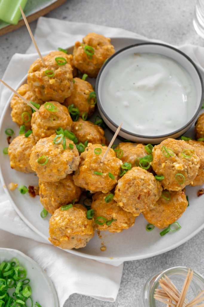 buffalo chicken meatballs on a white plate with toothpicks and a white napkin