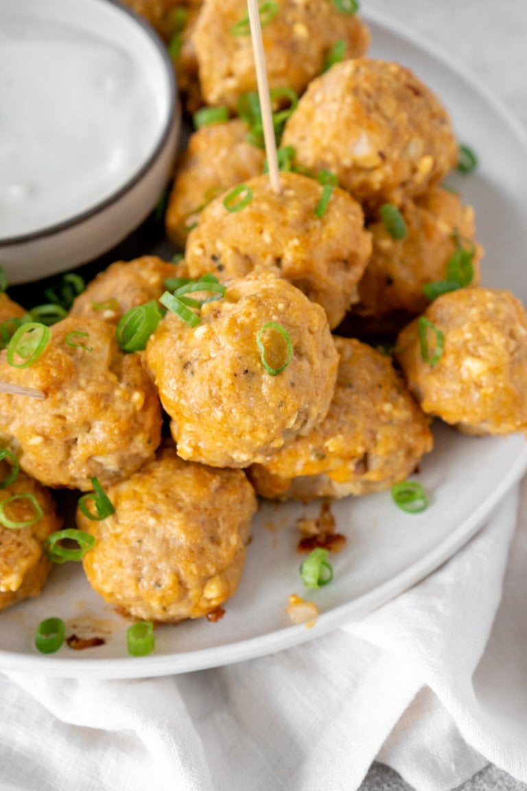 air fryer buffalo chicken meatballs on a white plate with ranch on the side