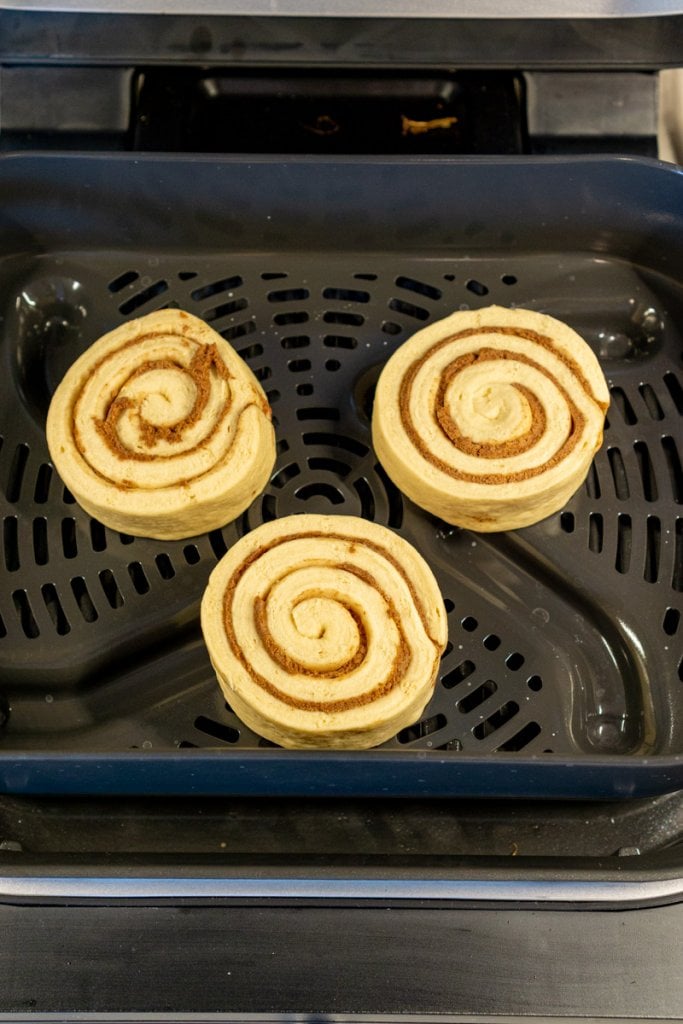 three cinnamon rolls in the air fryer basket