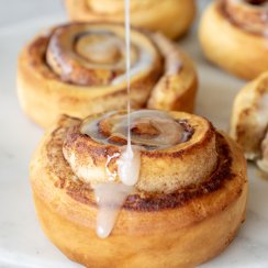 drizzling icing on an air fryer cinnamon roll