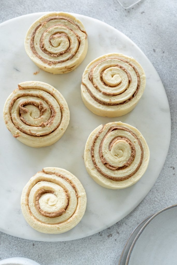 uncooked cinnamon rolls on a marble tray