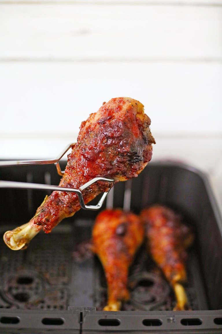 tongs holding an air fryer turkey leg