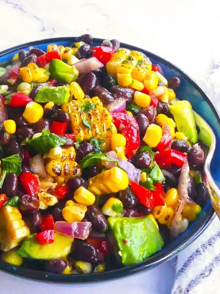Black bean salad with corn and avocado in a blue bowl.