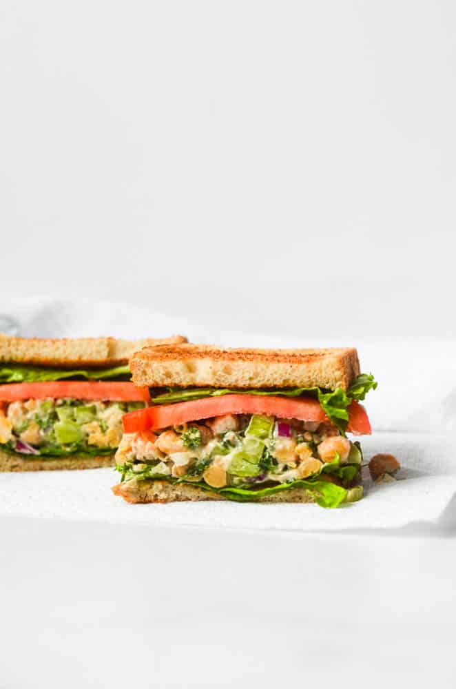 Chickpea "chicken" salad in sandwich form on a white background.