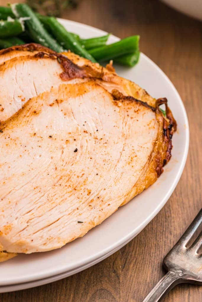 air fryer turkey breast sliced on a white plate with a fork