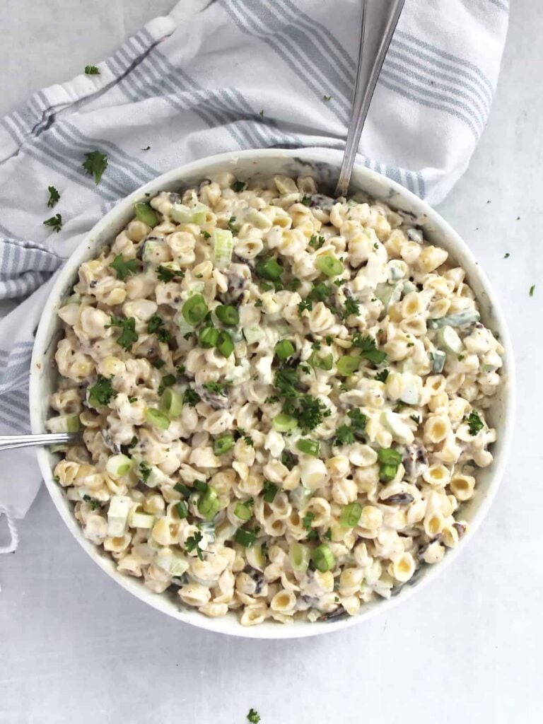 Bacon blue cheese pasta salad in a large white bowl with a towel near the bowl.