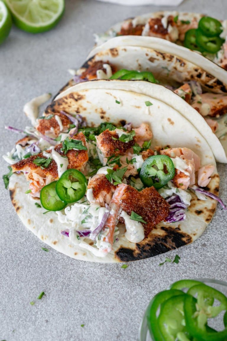 blackened salmon tacos with limes and jalapenos on the side