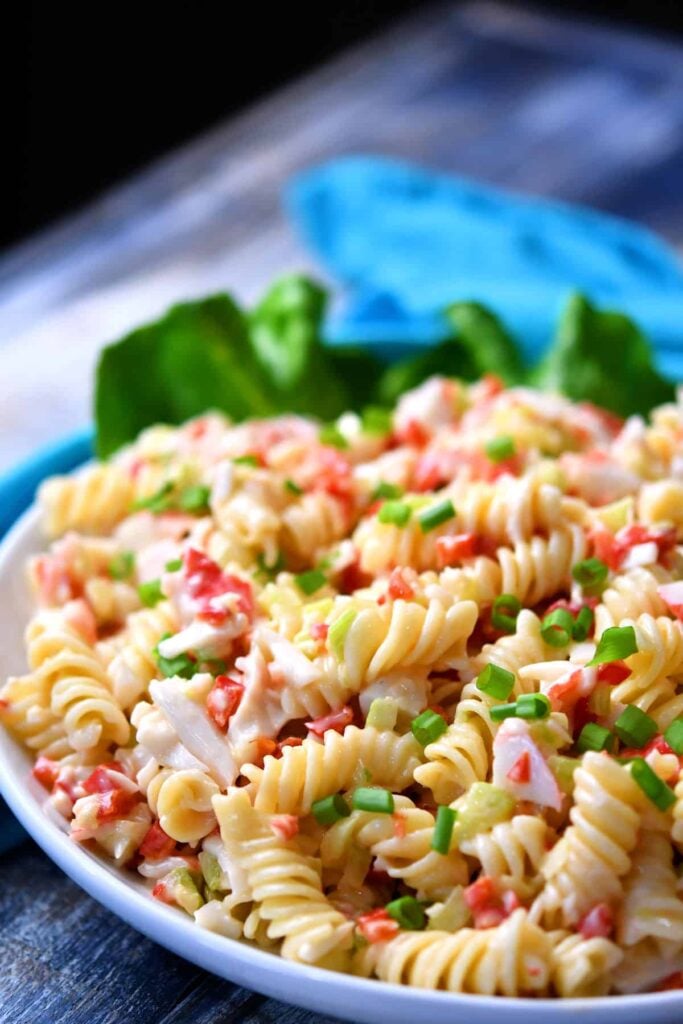Pasta salad with crab and green onions in a large bowl.