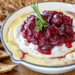 cranberry baked brie in a white cast iron with rosemary on top