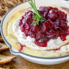 cranberry baked brie in a white cast iron with crackers around