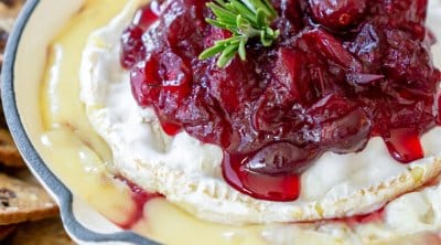 cranberry baked brie in a white cast iron with crackers around