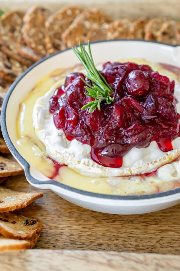 cranberry baked brie in a white cast iron with crackers around