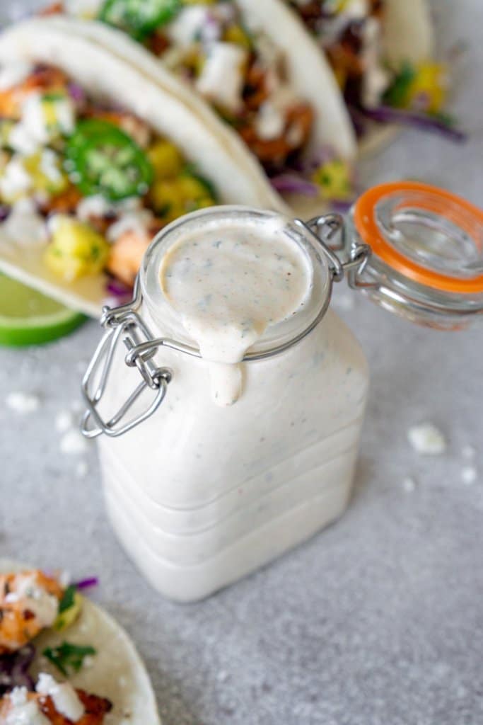 fish taco sauce in a glass jar with tacos