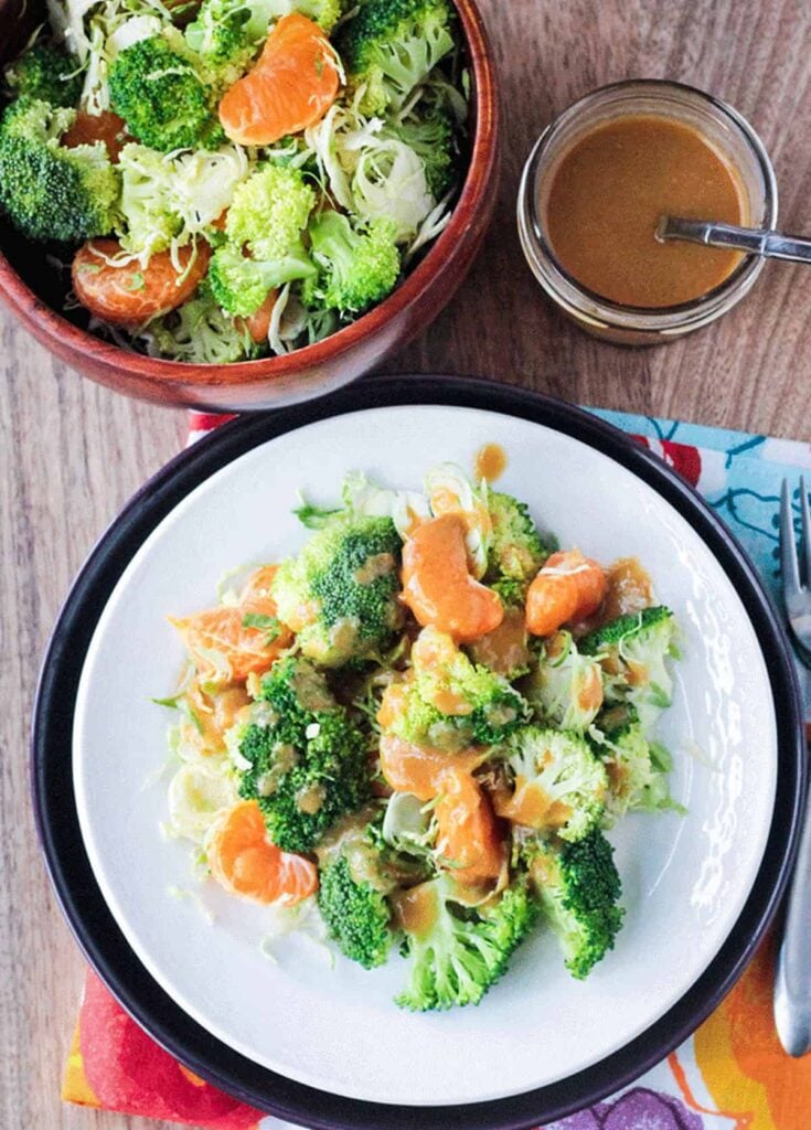 Vegan Brussels sprouts on a white plate with mandarin oranges.
