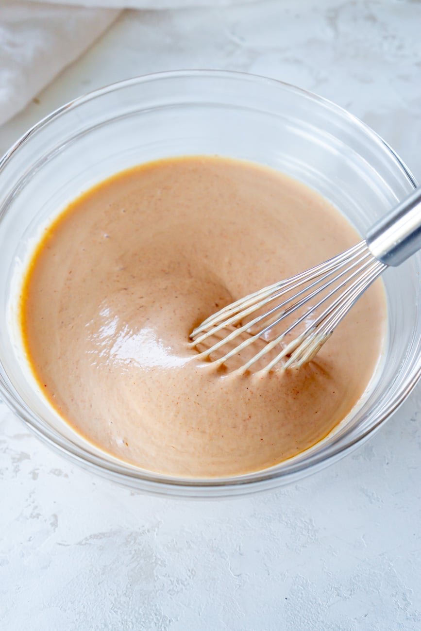 whisking yum yum sauce in a glass mixing bowl.