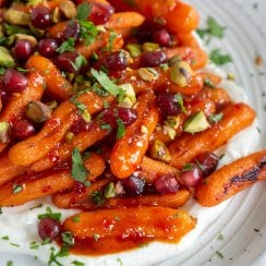 harissa honey roasted carrots on a plate with whipped feta and pistachios