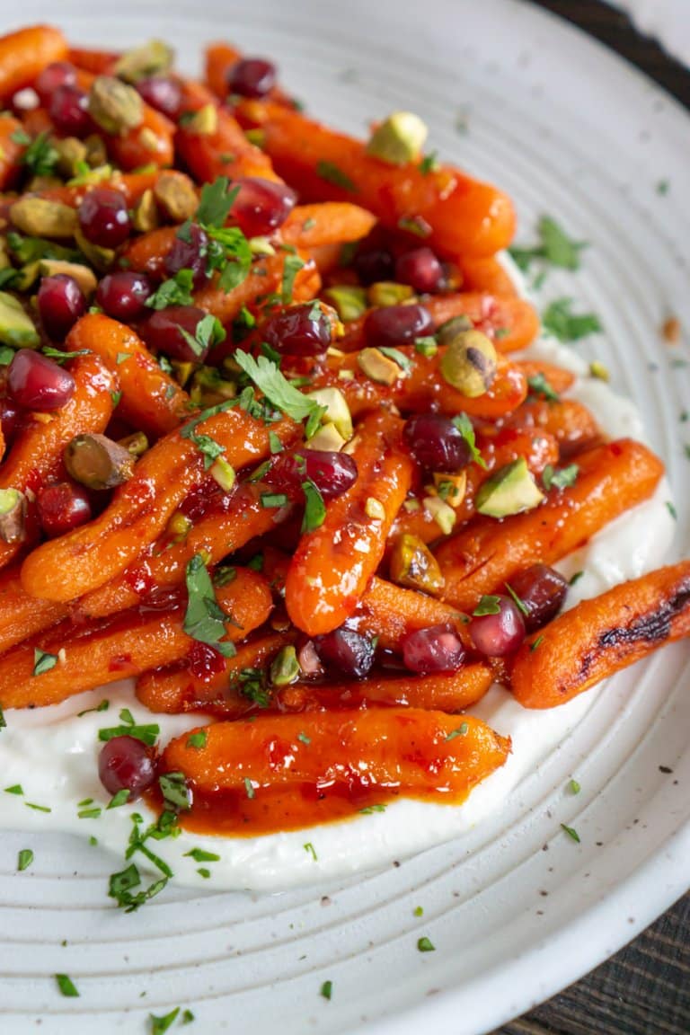 harissa honey roasted carrots on a plate with whipped feta and pistachios