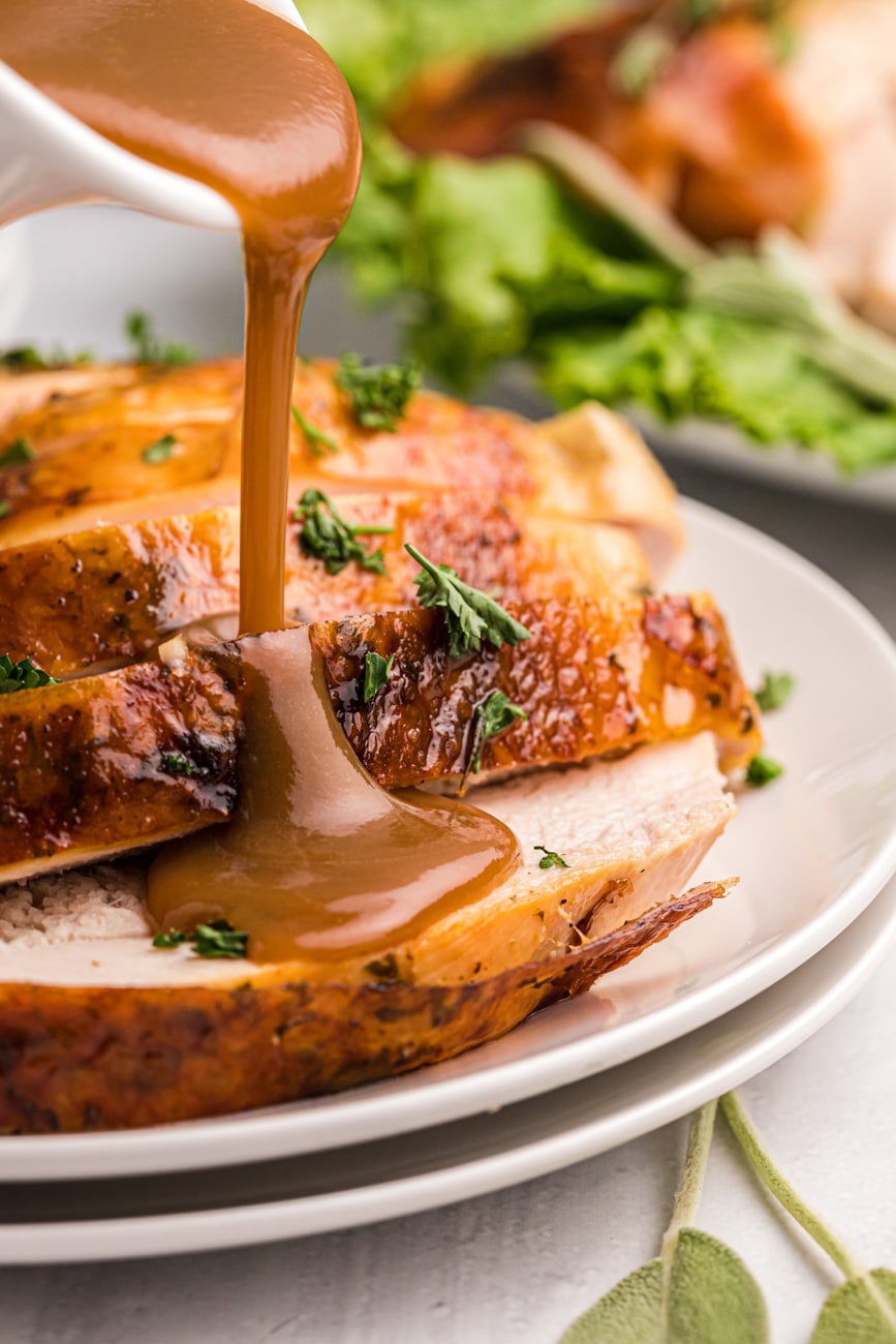 Pouring gravy over sliced roasted turkey.