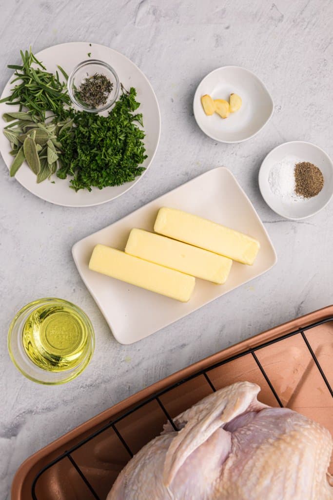 3 sticks of butter, herbs on a plate, and olive oil in a small bowl