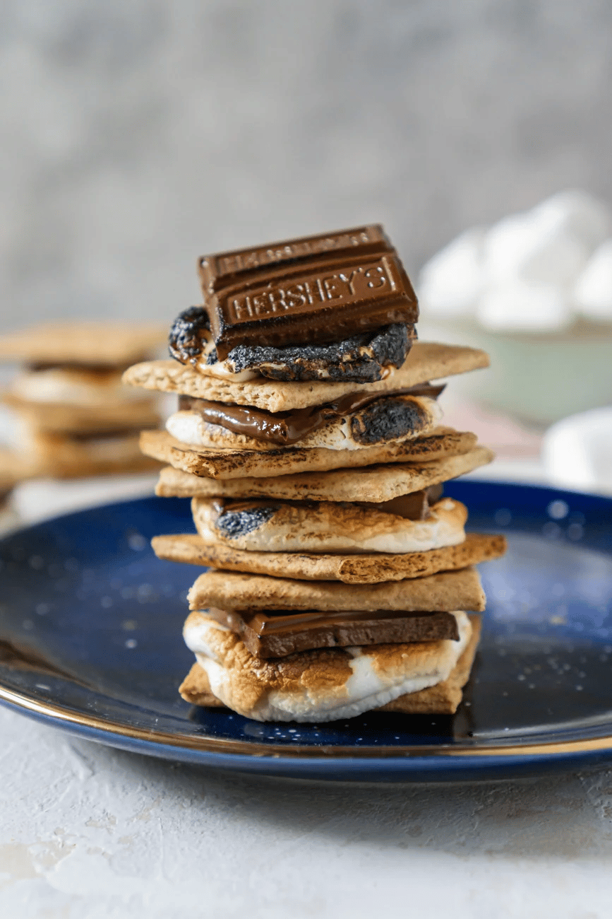 Cooked s'mores stacked on top of each other on blue plate.