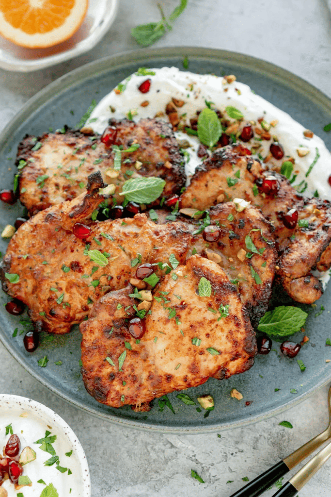 close up of cooked chicken on a blue serving dish covered in herbs and spices 