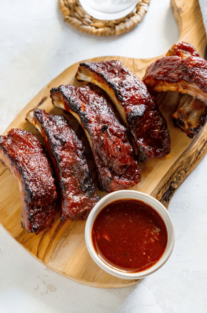 baby back ribs cut on wood platter with sauce