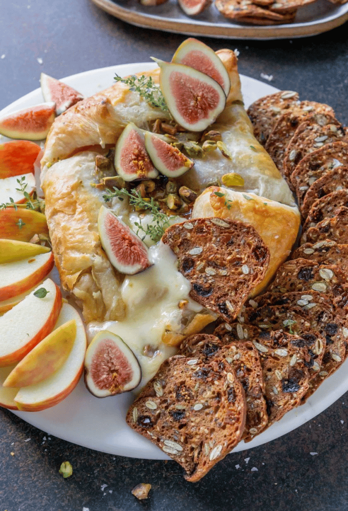 baked brie with fig jam on serving plate with apples and crisps 