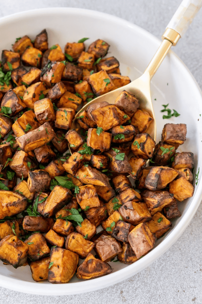 Air fried sweet potato cubes in white serving dish.