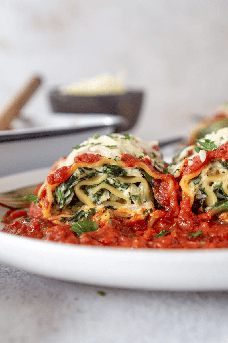 Close up of spinach lasagna roll with tomato sauce.