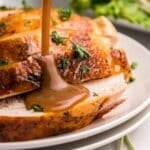 pouring gravy over sliced roasted turkey.